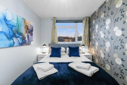 - une chambre avec un grand lit doté de draps bleus et d'oreillers bleus dans l'établissement Cadwell Serviced 4 Bedroom House with Parking Maidenhead by 360Stays, à Maidenhead