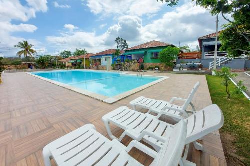 una piscina con 2 tumbonas junto a una casa en Lindo Privê 04 Suítes com AR, 5WC e Grande Piscina en Gravatá
