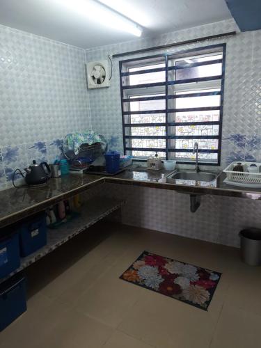 a kitchen with a counter and a sink and a window at Panorama Homestay in Jeram