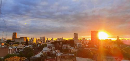 a city skyline with the sun setting in the sky at Palermo Panoramic in Buenos Aires