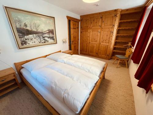 a bed in a room with a painting on the wall at Chesa Coronella in La Punt-Chamues-ch