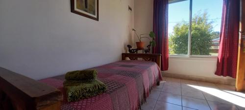 a bedroom with a bed with a chair and a window at Cabañas Mérida Ruta 66 in El Hoyo