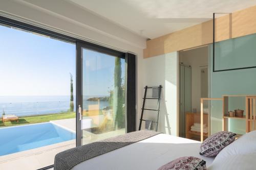 een slaapkamer met een bed en uitzicht op de oceaan bij Villa Ammos in Ferma