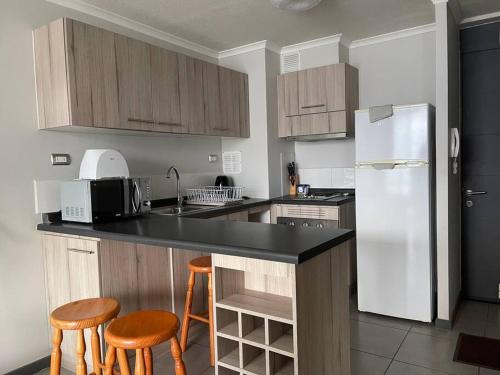 a kitchen with a white refrigerator and wooden cabinets at Apartamento junto a la playa - Vistas Increíbles in Coquimbo