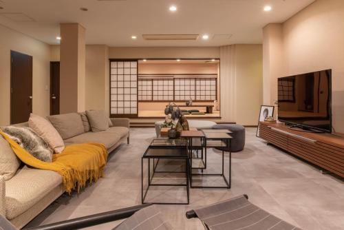 sala de estar con sofá y TV en Bijou Suites AI PREMIUM en Osaka