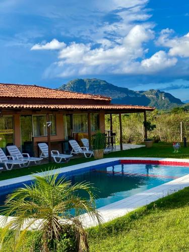 a house with a swimming pool and mountains in the background at Casa de Campo - Rancho Braga Aguiar in Ibicoara