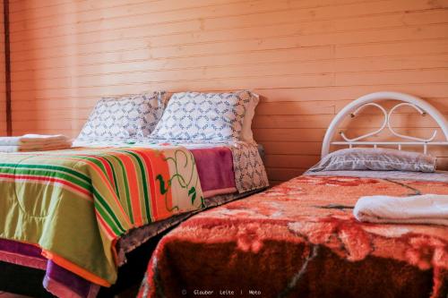 a bedroom with two beds and a wooden wall at Pousada Sítio Do Trevo in Urubici