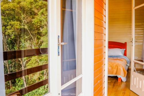 eine Tür, die zu einem Schlafzimmer mit einem Fenster führt in der Unterkunft Pousada Sítio Do Trevo in Urubici