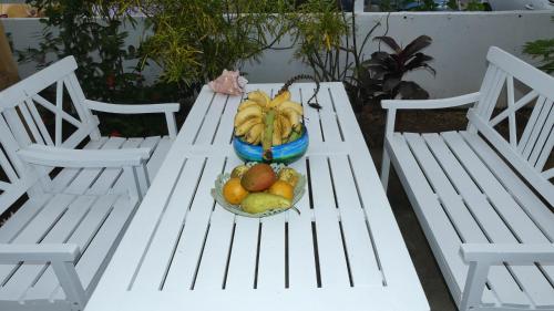 a white picnic table with a bowl of fruit on it at Le Colibri et le Frangipanier in La Trinité