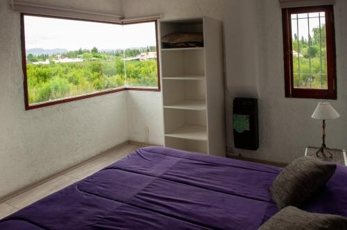 a bedroom with a purple bed and a window at Complejo BenjaLuna in San Rafael