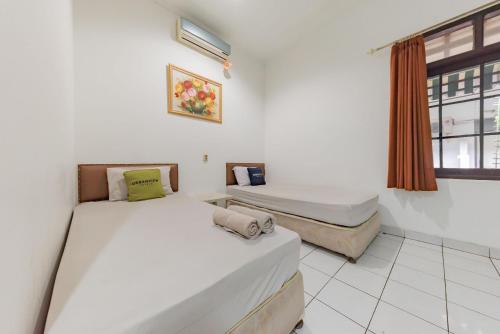 Duas camas num quarto com uma janela em Urbanview Hotel Pondok Kurnia Cijagra Bandung em Bandung