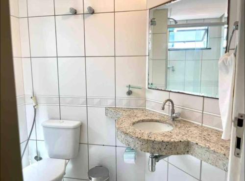 a bathroom with a sink and a toilet and a mirror at Biarritz temporadalitoranea in São Luís