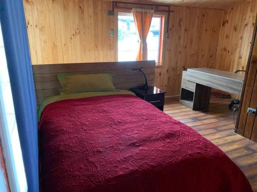 - une chambre avec un lit et une couverture rouge dans l'établissement Casa Centro Dalcahue, à Dalcahue