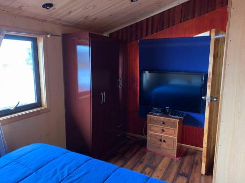 a bedroom with a bed and a flat screen tv at Casa Centro Dalcahue in Dalcahue