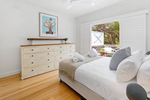 a bedroom with a bed and a dresser with a window at Seaspray in Sorrento
