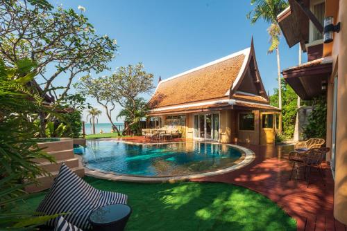 a swimming pool in front of a house at Gala Beachfront Villa in Pattaya South