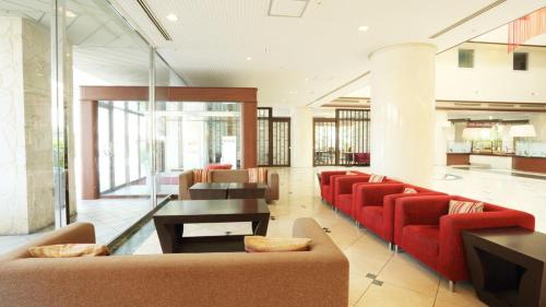 eine Lobby mit roten Sofas, Tischen und Fenstern in der Unterkunft Smile Hotel Naha City Resort in Naha