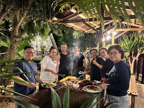 um grupo de pessoas à volta de uma mesa com comida em Lang Homestay - Venuestay em Mộc Châu