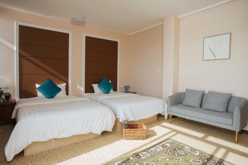 a bedroom with two beds and a blue chair at Seaward Sea view double room with balcony in Koror