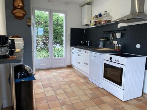 Il comprend une cuisine avec des appareils électroménagers blancs et du carrelage. dans l'établissement Maison calme avec jardin, proche plages et centre, 2 chambres, 4 couchages, ménage inclus - FR-1-246A-163, à Saint-Denis-dʼOléron