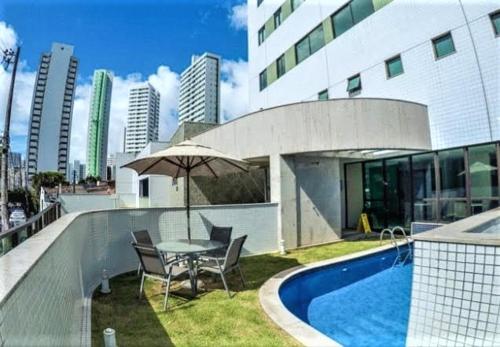 uma mesa com cadeiras e um guarda-sol ao lado de um edifício em Apto moderno e bem localizado no Recife