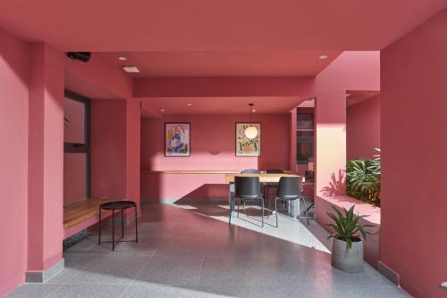 a room with pink walls and a table and chairs at M Village Living Hồ Biểu Chánh in Ho Chi Minh City