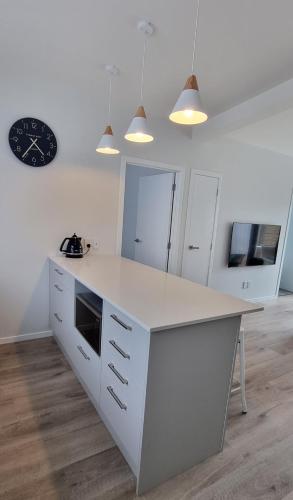 a kitchen with a white counter and a clock on the wall at Cosy on Korari in Mangakino in Mangakino