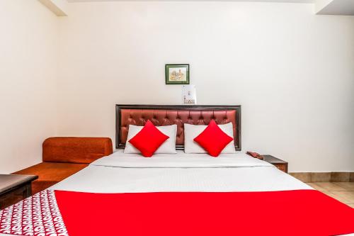 a bed with red pillows and a red blanket at Super OYO Hotel City Castle in New Delhi