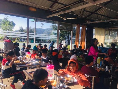 a group of children sitting at tables in a restaurant at SnowDrop eco resort in Chail