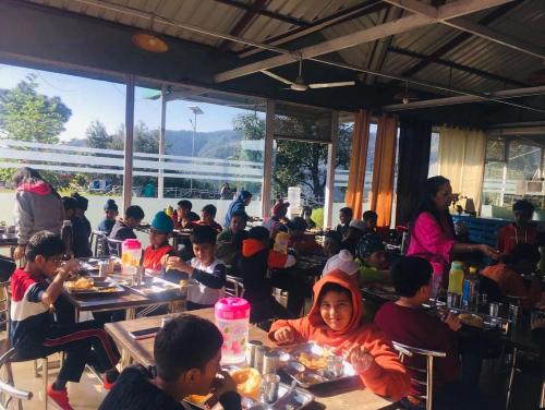 un groupe d'enfants assis à table dans un restaurant dans l'établissement SnowDrop eco resort, à Chail