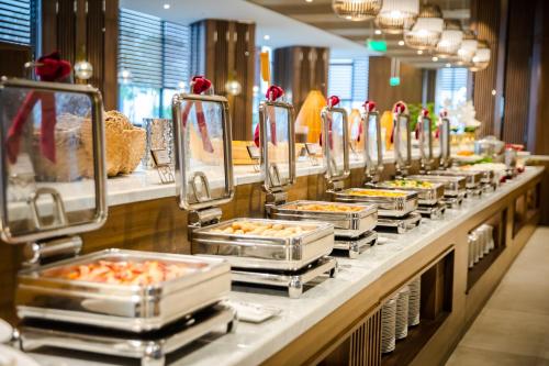 Muong Thanh Luxury Ha Long Centre Hotel في ها لونغ: طابور بوفيه مع العديد من صواني الطعام