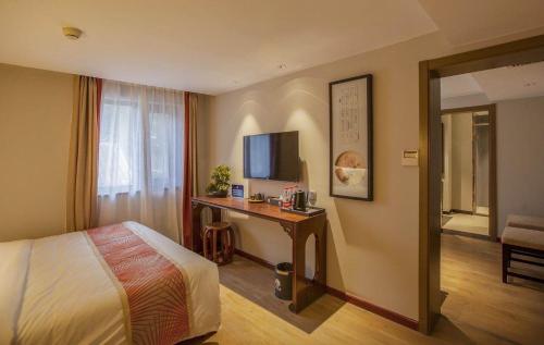 a hotel room with a bed and a desk with a television at Guxiang Bushe - Nanluoguxiang Branch in Beijing