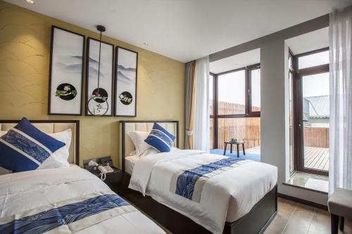 sypialnia z 2 łóżkami i oknem w obiekcie Tangfu Boutique Hotel Nanluoguxiang Drum Tower Houhai w Pekinie