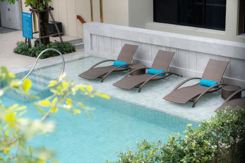 a group of chairs sitting next to a swimming pool at Centara Life Hotel Bangkok Phra Nakhon in Bangkok