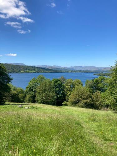 a field of grass with a lake in the background at Troutbeck Hot Tub Lodge 4 in Windermere