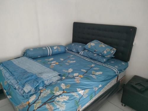 Bett mit blauer Bettdecke und Kissen darauf in der Unterkunft Giri Home & Travel in Ciwidey