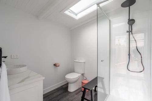 a white bathroom with a toilet and a glass shower at Two Worlds Townhouse in Launceston