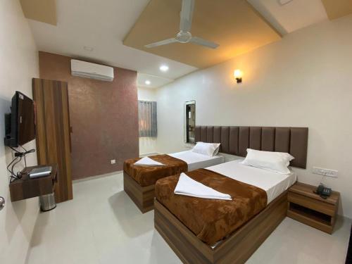 a bedroom with two beds and a flat screen tv at HOTEL DIVINE in Mumbai