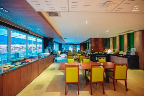 a restaurant with yellow chairs and tables and a buffet at Centara Pattaya Hotel in Pattaya