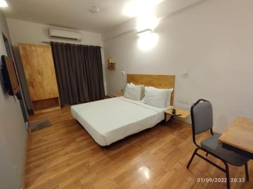 a bedroom with a white bed and a desk and a chair at UPAR Hotels Indiranagar in Bengaluru