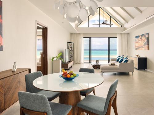 a living room with a table and chairs and the ocean at Nova Maldives in Dhangethi