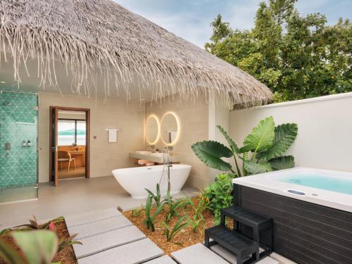 a bathroom with a tub and a toilet and a sink at Nova Maldives in Dhangethi