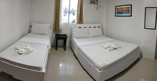 two beds in a white room with flowers on them at Island Hop Inn in El Nido