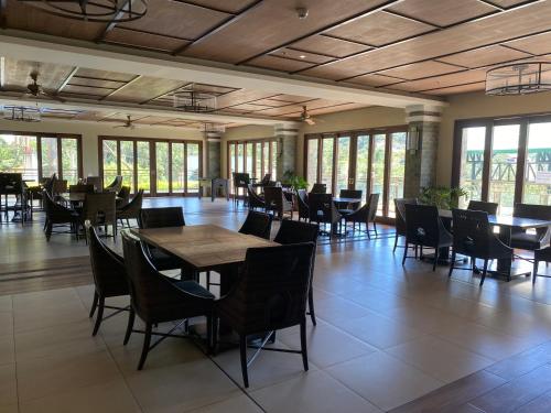 a dining room with tables and chairs and windows at Condo Suite Near JohnHay MinesView TheMansion in Baguio