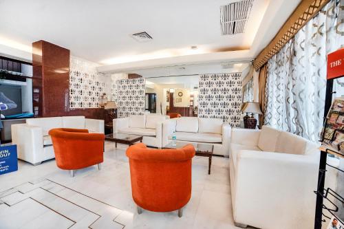 uma sala de espera com mobiliário branco e cadeiras laranja em FabHotel BMK Grand em Nova Deli