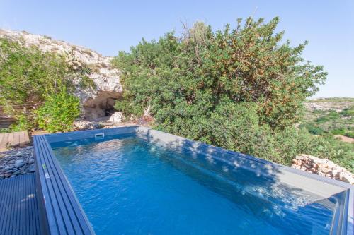 ein blauer Pool mit Bäumen im Hintergrund in der Unterkunft POOL & SPA - wellness VILLA St Martin - Happy Rentals in San Pawl il Bahar