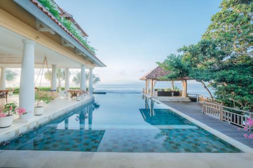 een overloopzwembad van het resort met uitzicht op het water bij Raaga Samudra Villa in Padangbai