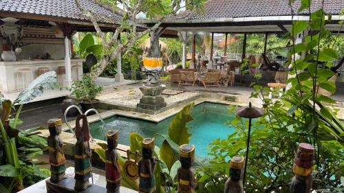 a swimming pool in a garden with a fountain at Chakra Living Ubud in Ubud