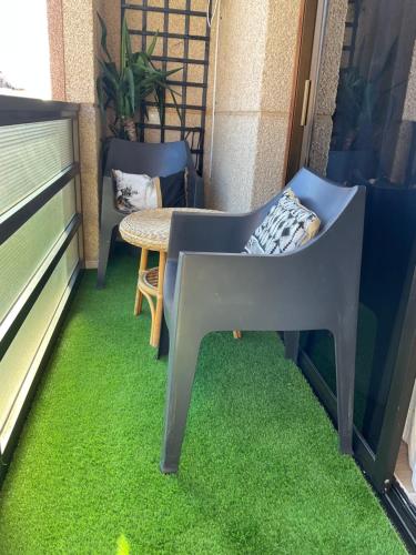 a balcony with green grass and a chair and a table at Arena y Calma Jandia con aire acondicionado in Morro del Jable