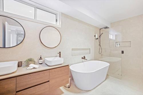 ein Badezimmer mit zwei Waschbecken, einer Badewanne und einem Spiegel in der Unterkunft 'Devan House' Family Retreat with Games Room in Mudgee